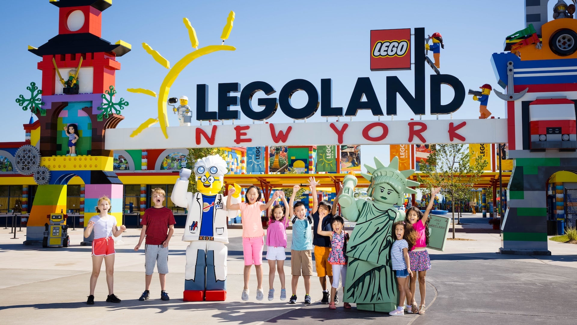 Kids jumping with lego characters in front of the entrance to LEGOLAND New York